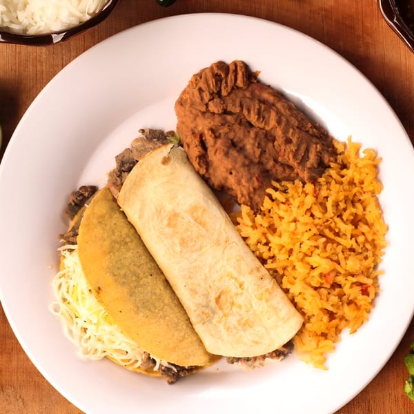 Mexican combo plate with a taco, burrito, refried beans, and orange rice on a white plate.