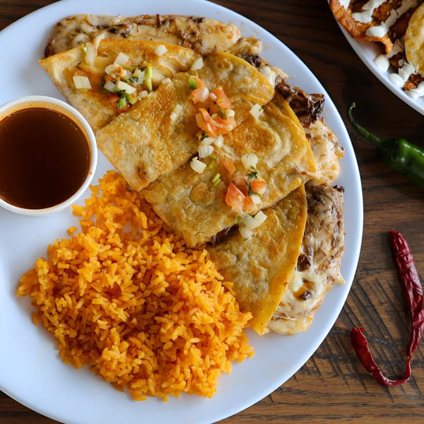 A plate of Taqueria Los Portales' quesadillas with rice, salsa, and a side of dipping sauce.