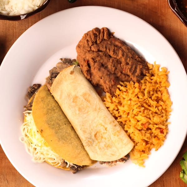 Mexican combo plate with a hard shell taco, a soft taco, refried beans, and yellow rice.